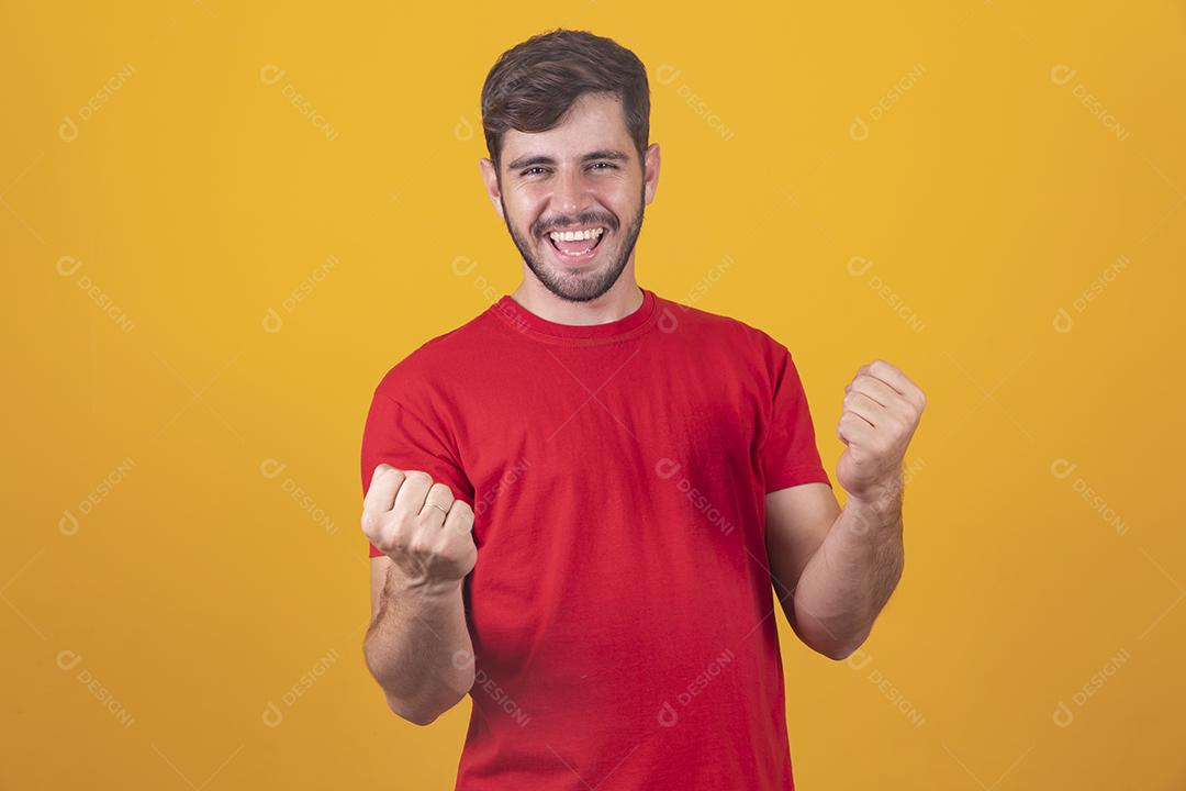 jovem comemorando a vitória sobre fundo amarelo