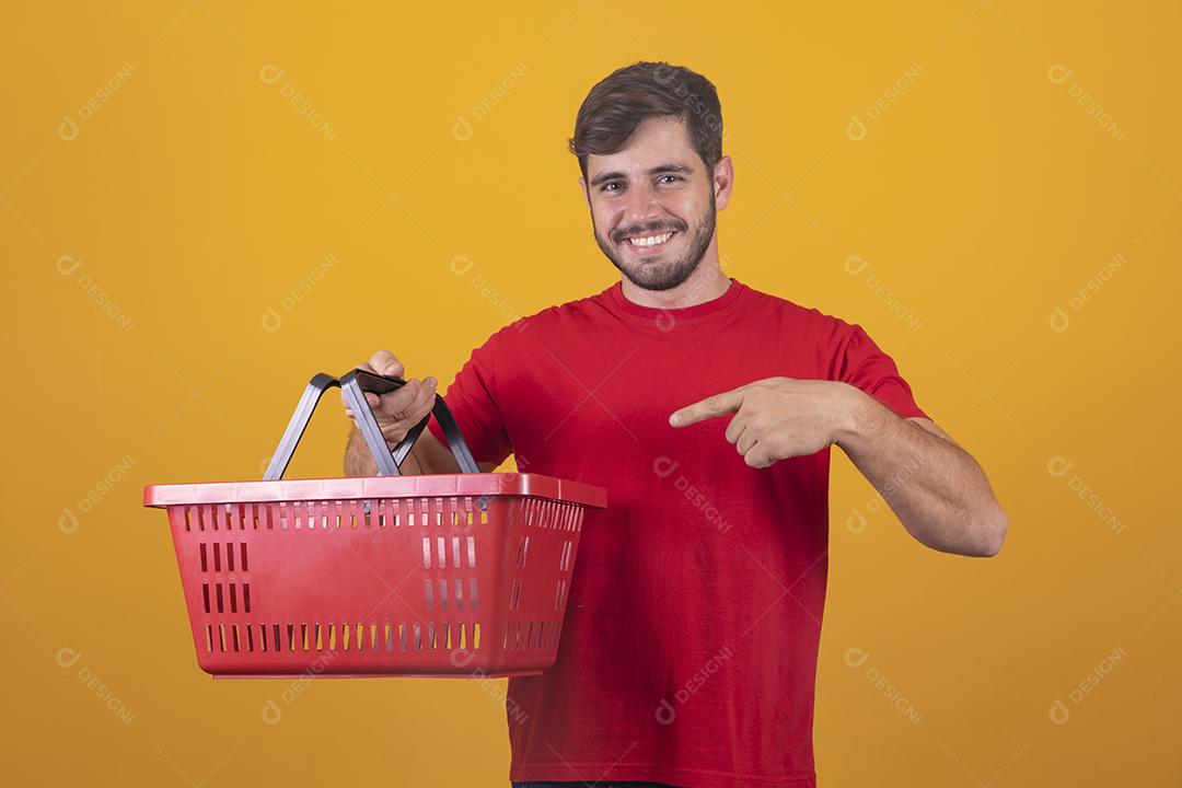 homem com cesta de supermercado em fundo amarelo
