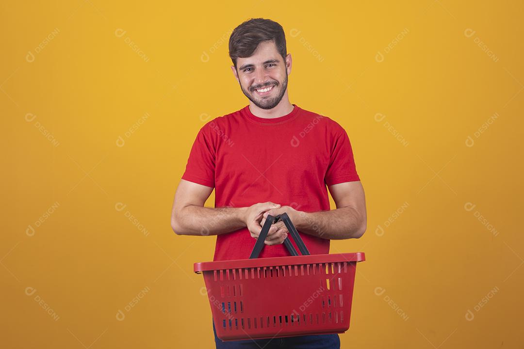 homem com cesta de supermercado em fundo amarelo