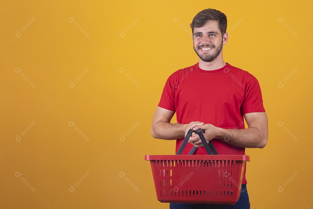 homem com cesta de supermercado em fundo amarelo