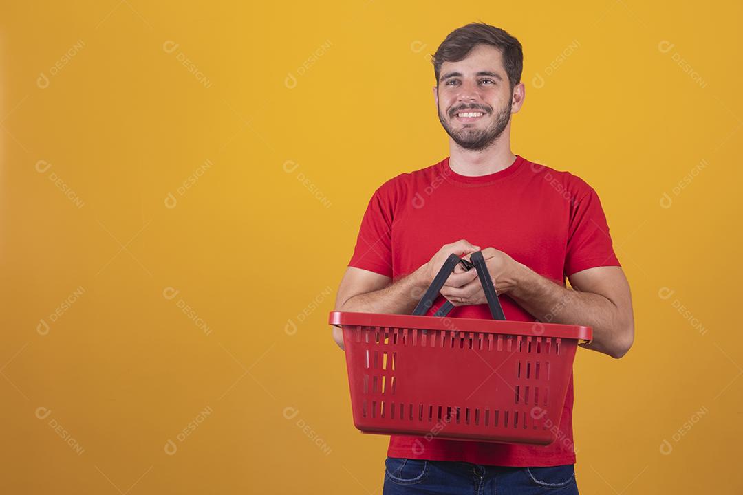 homem com cesta de supermercado em fundo amarelo