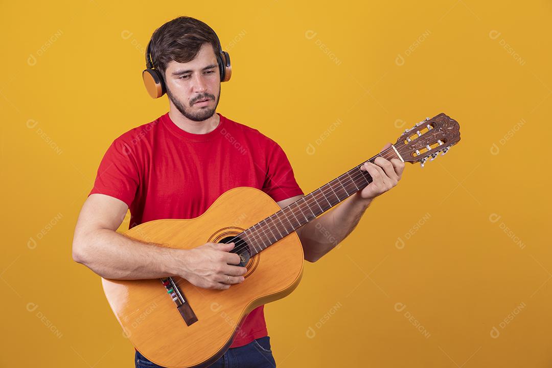 jovem tocando guitarra em fundo amarelo