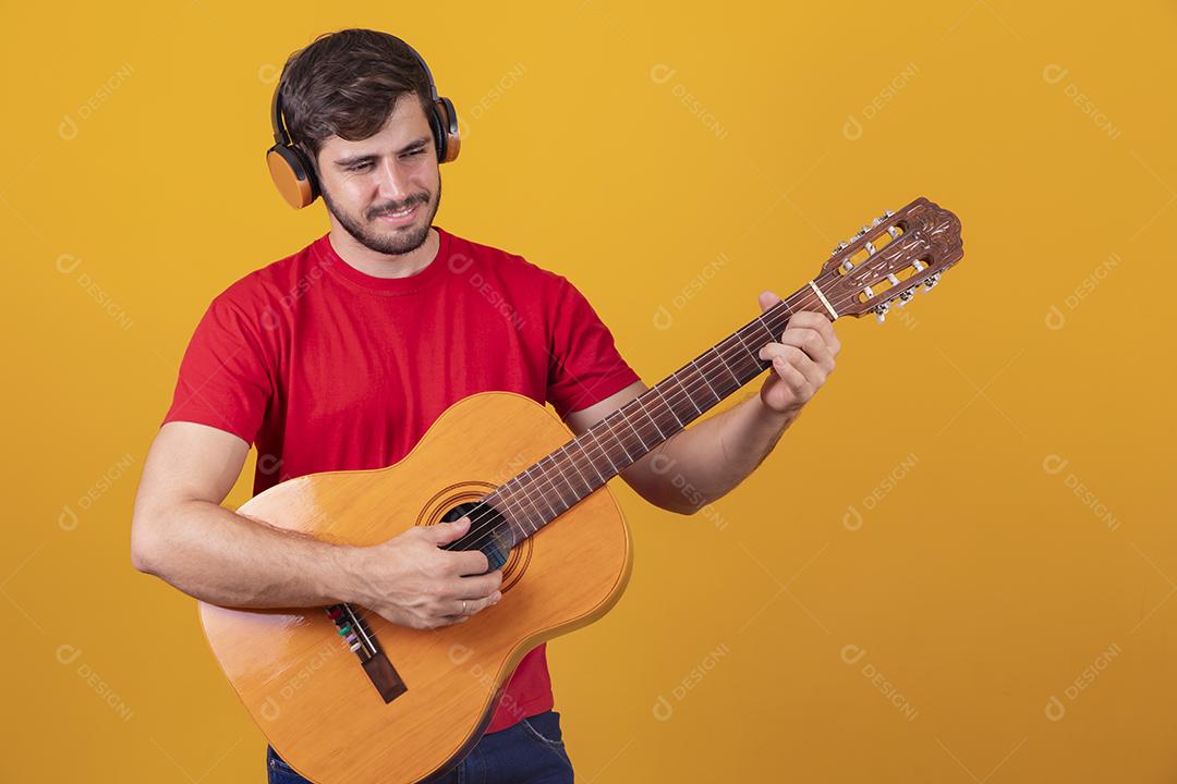 jovem tocando guitarra em fundo amarelo