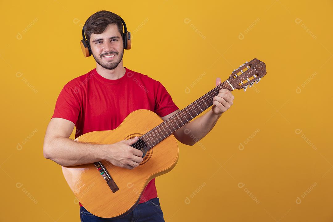 jovem tocando guitarra em fundo amarelo