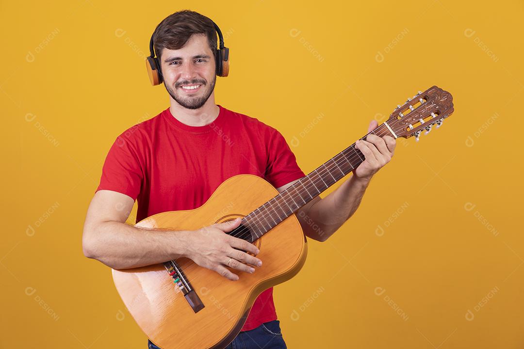 jovem tocando guitarra em fundo amarelo