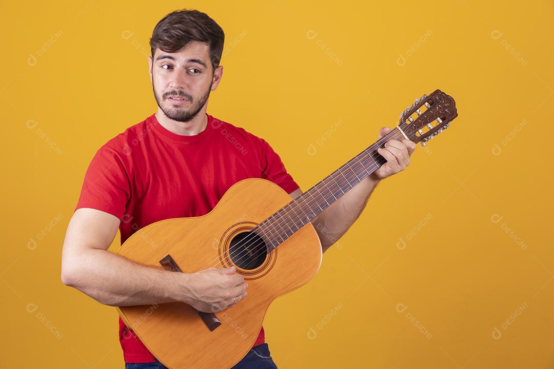 jovem tocando guitarra em fundo amarelo