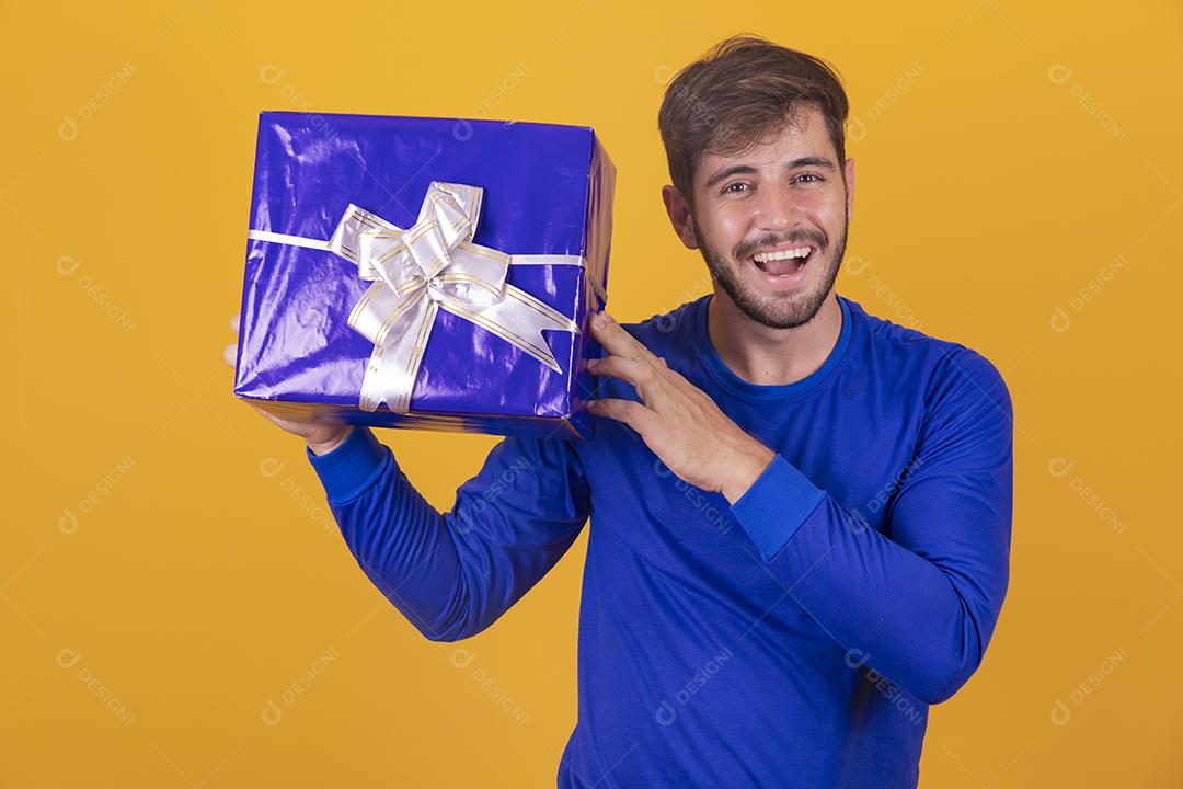 jovem sorridente segurando uma caixa de presente em fundo amarelo jovem segurando uma caixa de presente em fundo amarelo