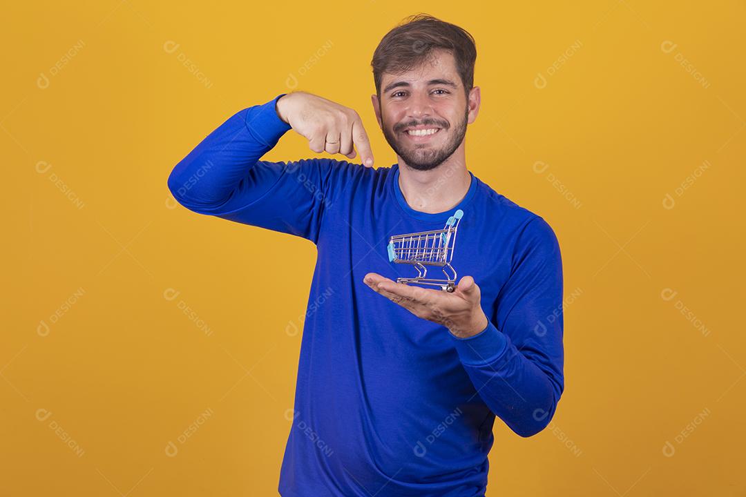 Homem jovem segurando um mini carrinho de compras