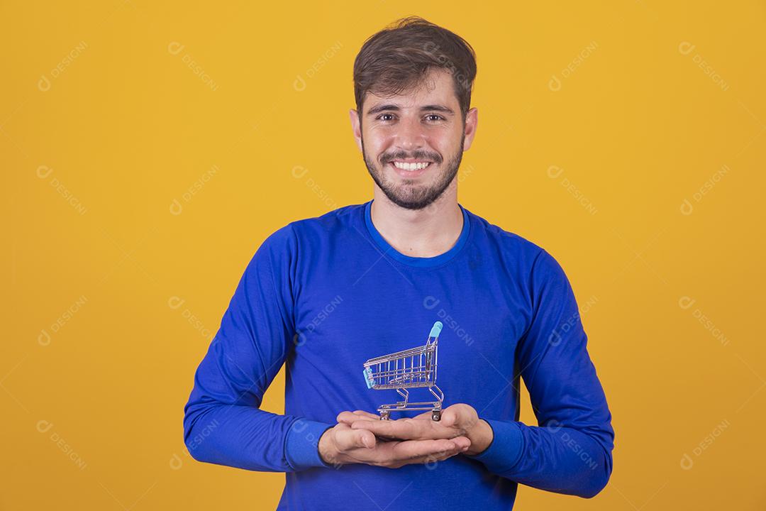 Homem jovem segurando um mini carrinho de compras