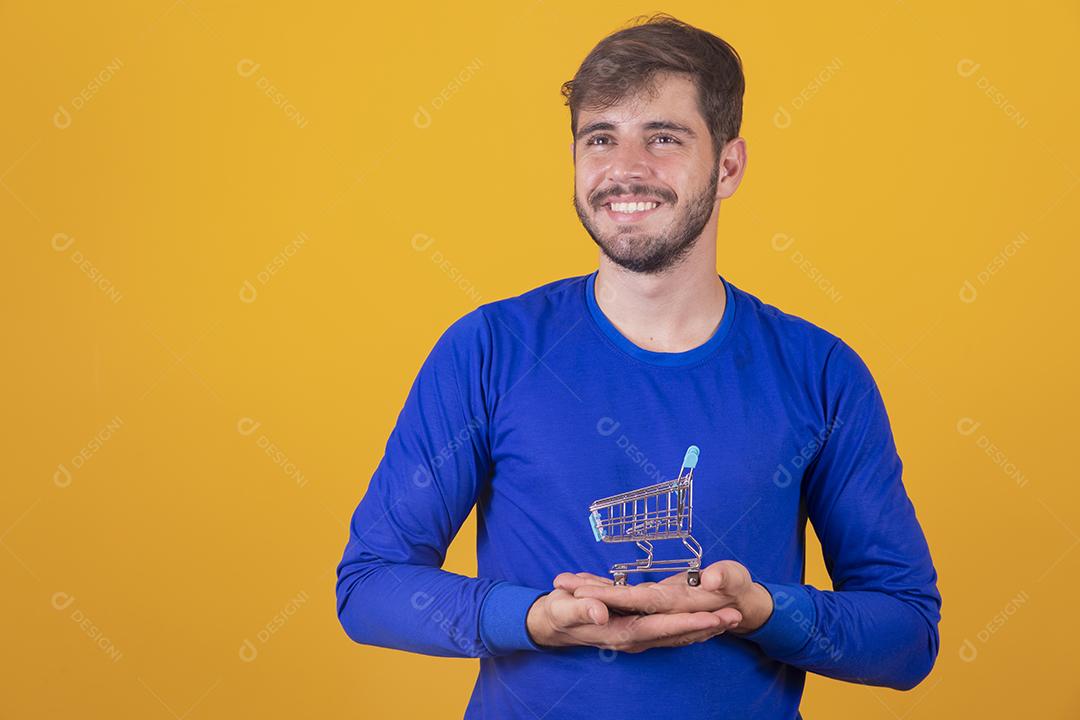 Homem jovem segurando um mini carrinho de compras