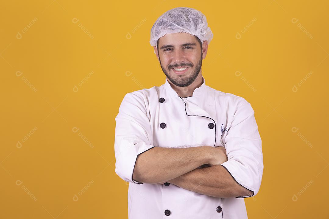 Smiling young male chef cook or baker in white uniform shirt posing isolated on yellow background studio portrait. Cooking food concept. Mock up copy space. Whipping eggs by hitting the bowl