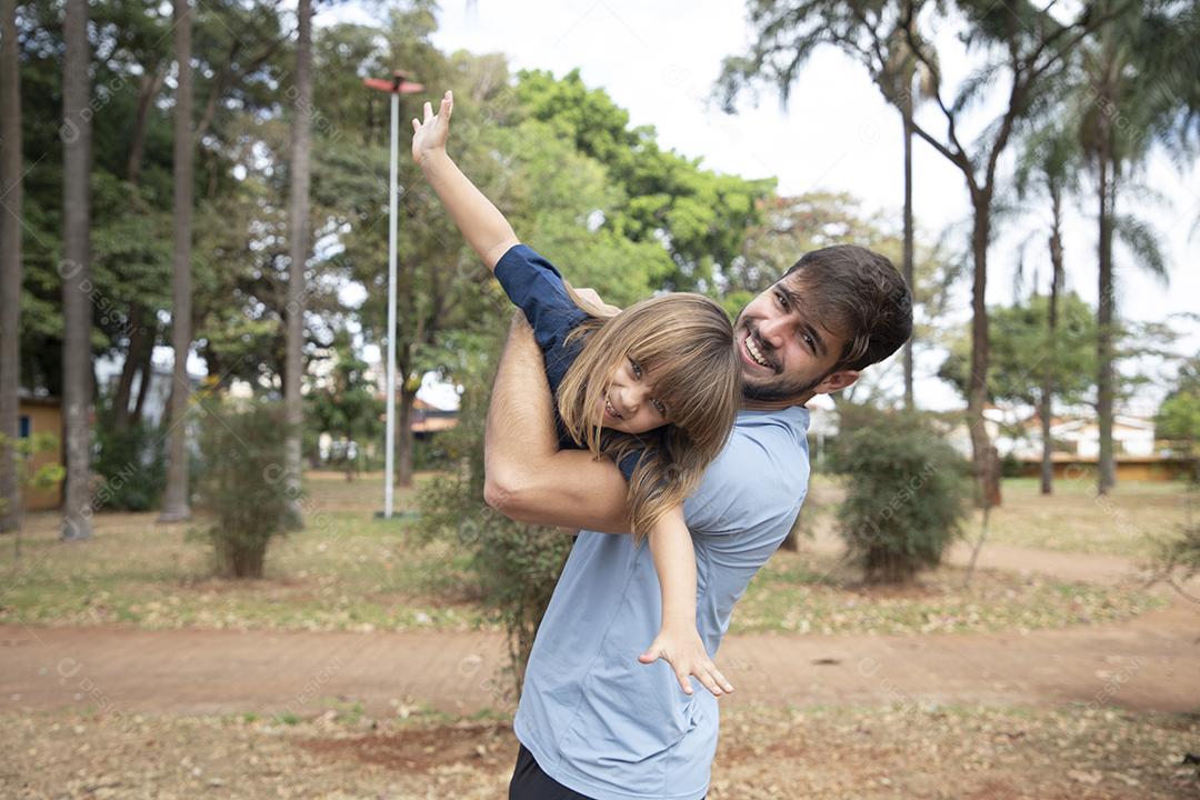 Pai e filha brincando no parque. Feliz Dia dos Pais Pai jogando em um avião com sua filha nos braços