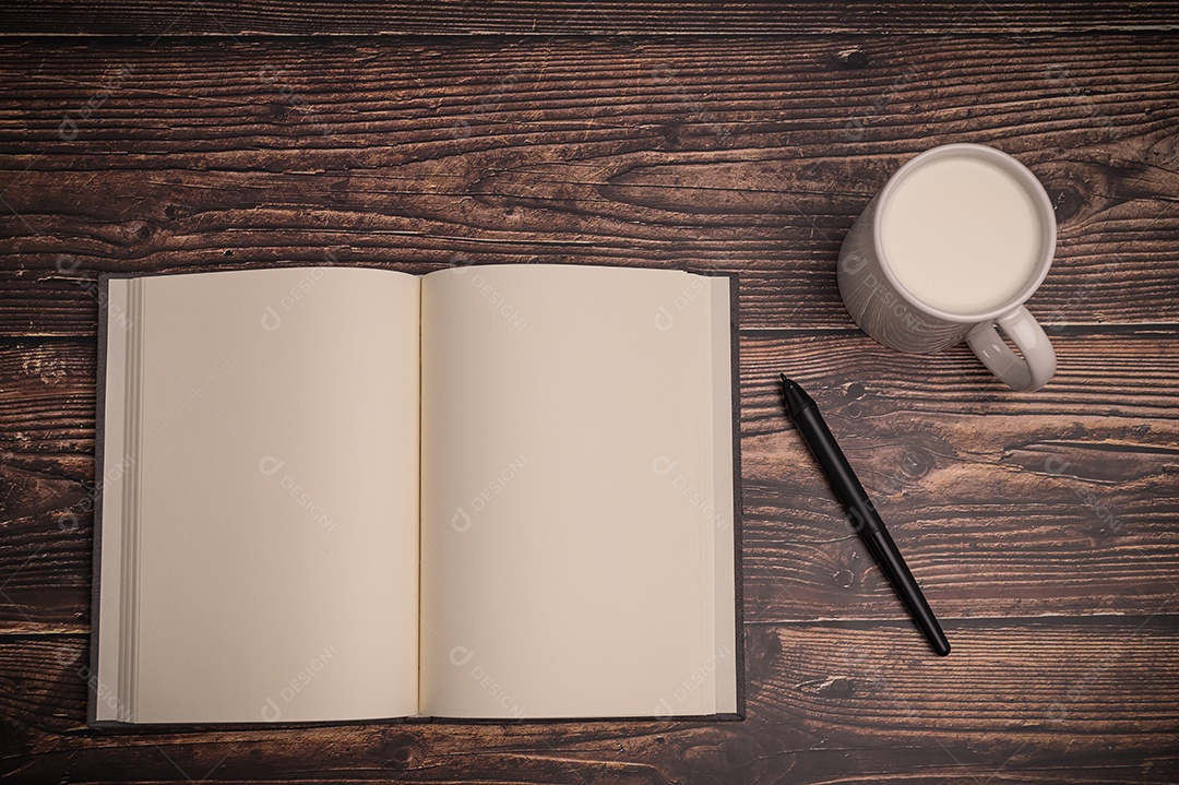 Caderno e um copo de leite estão sobre a mesa.