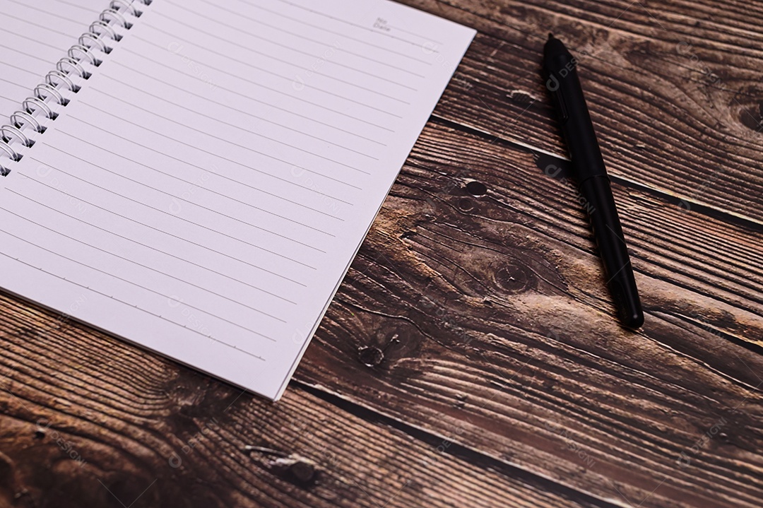 Caderno e um copo de leite estão sobre a mesa.