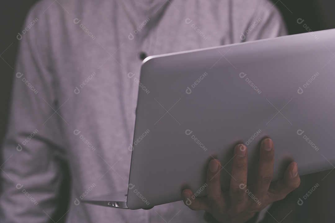 Homem em pé usando um laptop