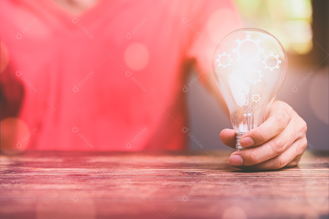 Mão de um homem com uma lâmpada E há um ícone de engrenagem