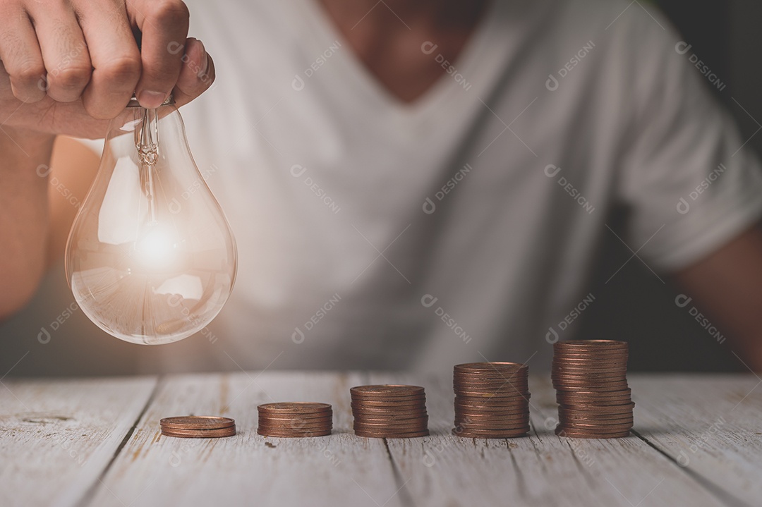 Empresário segurando a ideia de pilha de dinheiro de lâmpada economizando energia