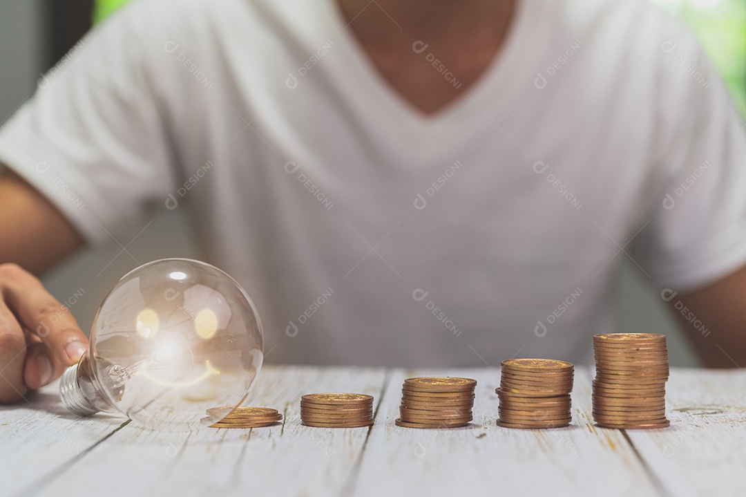 Empresário segurando a ideia de pilha de dinheiro de lâmpada economizando energia