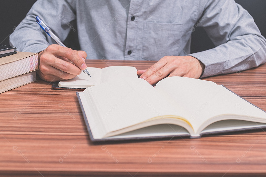 Pessoa escrevem um livro em sua mesa