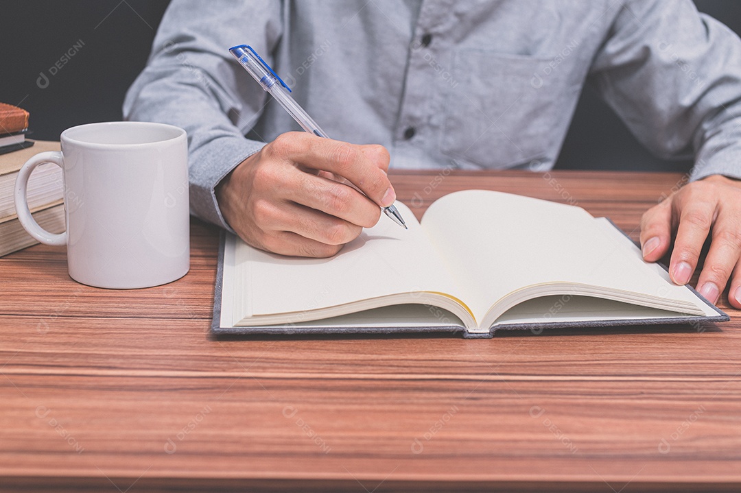 Pessoa escrevem um livro em sua mesa