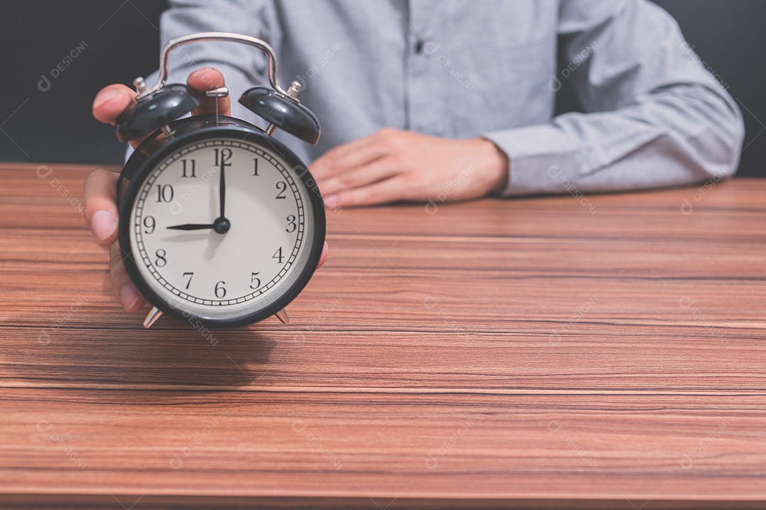 Mão humana segura um relógio mostrando a hora