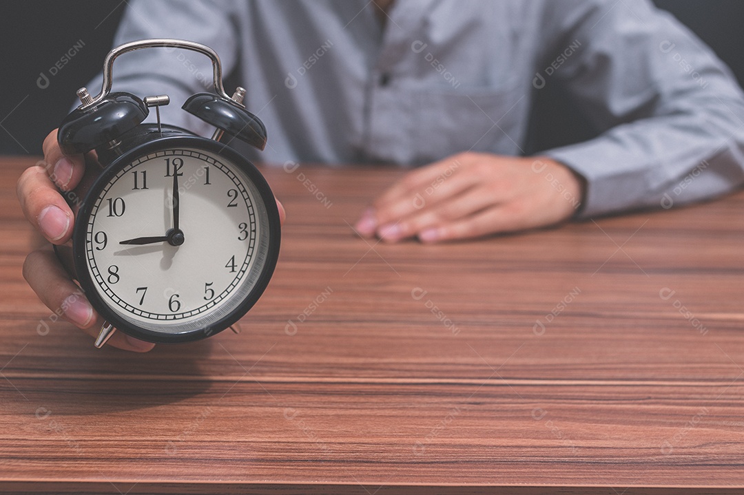 Mão humana segura um relógio mostrando a hora