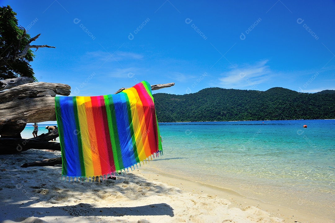 Arco-íris de tecido na praia e céu azul