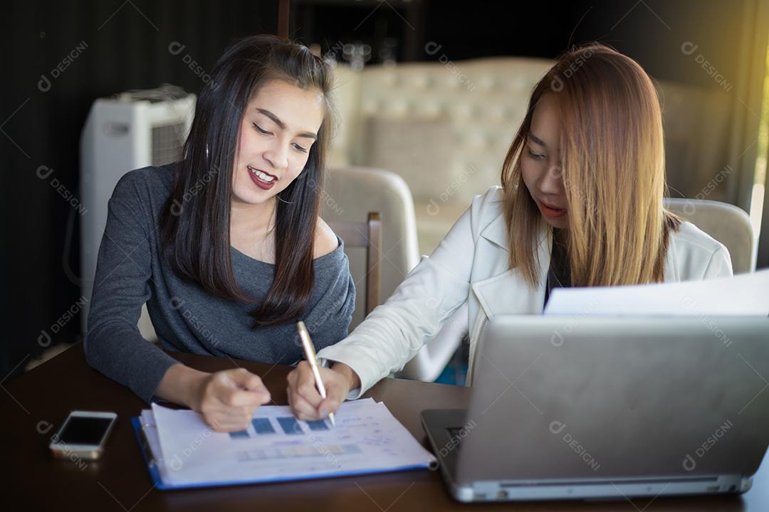 Duas mulheres de negócios asiáticas usando notebook trabalhando e discussão do importante contrato no escritório, foco suave