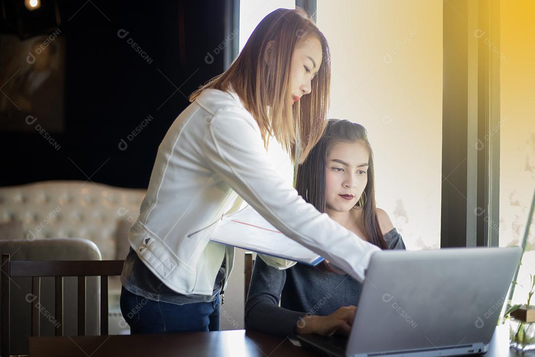 Duas mulheres de negócios asiáticas usando notebook trabalhando e discussão do importante contrato no escritório, foco suave