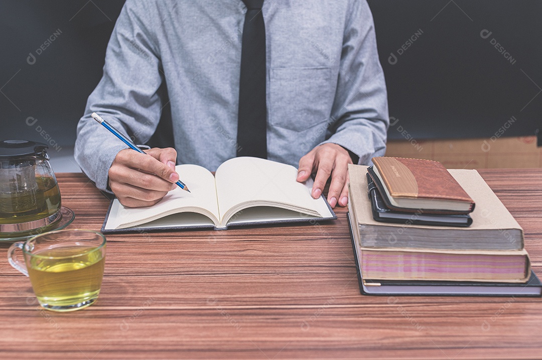 Homem está escrevendo em sua mesa