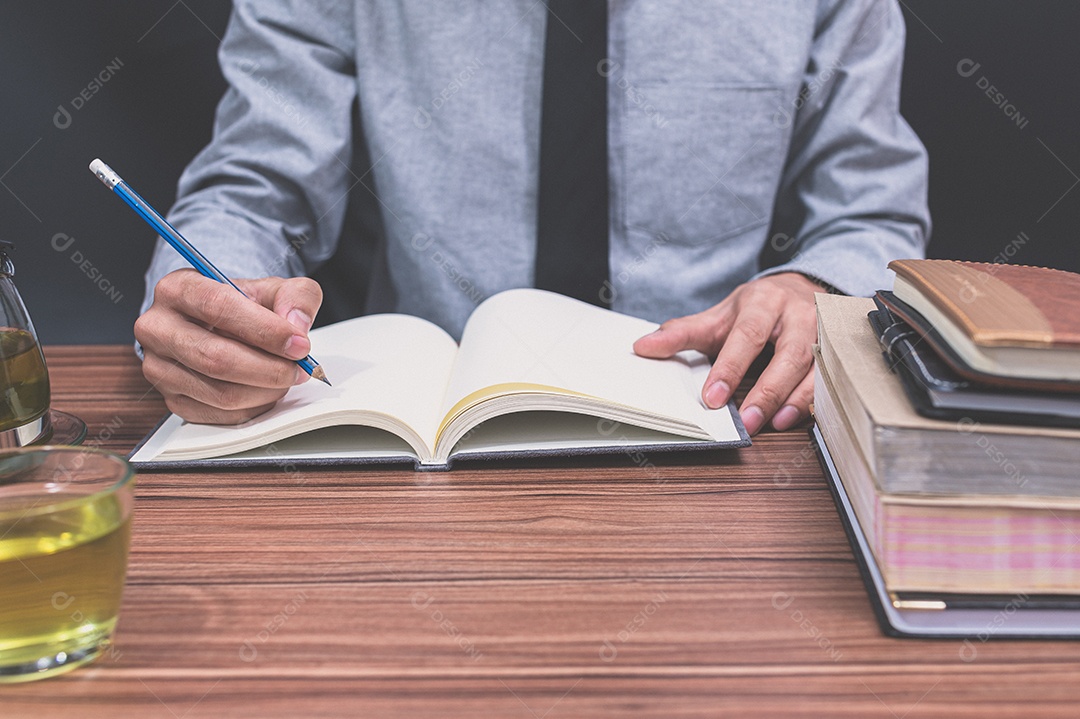 Homem está escrevendo em sua mesa