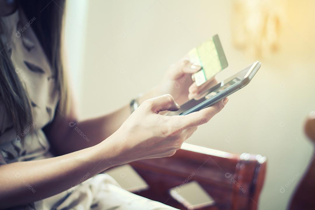 Mulher asiática usando telefone inteligente e cartão de crédito compras on-line, foco seletivo na mão