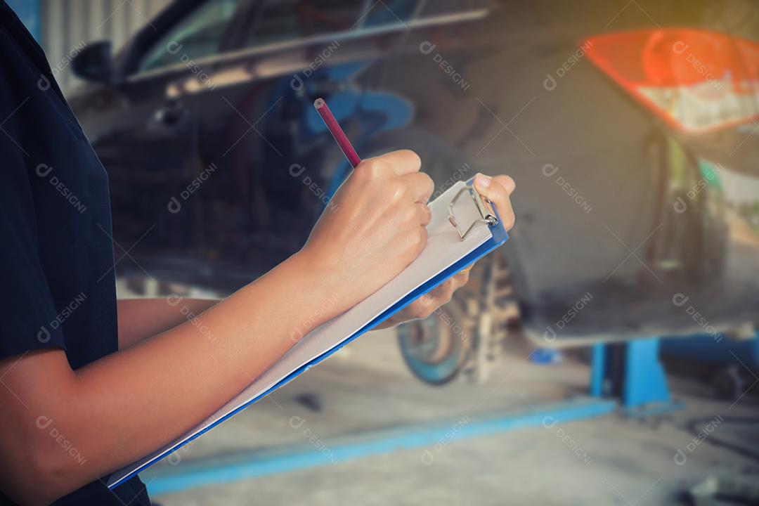 As engenheiras e técnicas asiáticas estão verificando o mecânico e inspecionando um carro na oficina de automóveis a lista no quadro