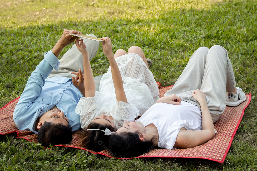 A família asiática está usando o tablet no tapete.