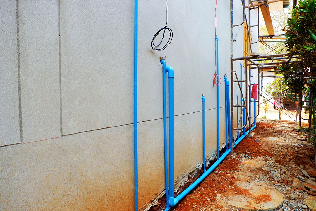 Canos de água de PVC são instalados atrás da casa.
