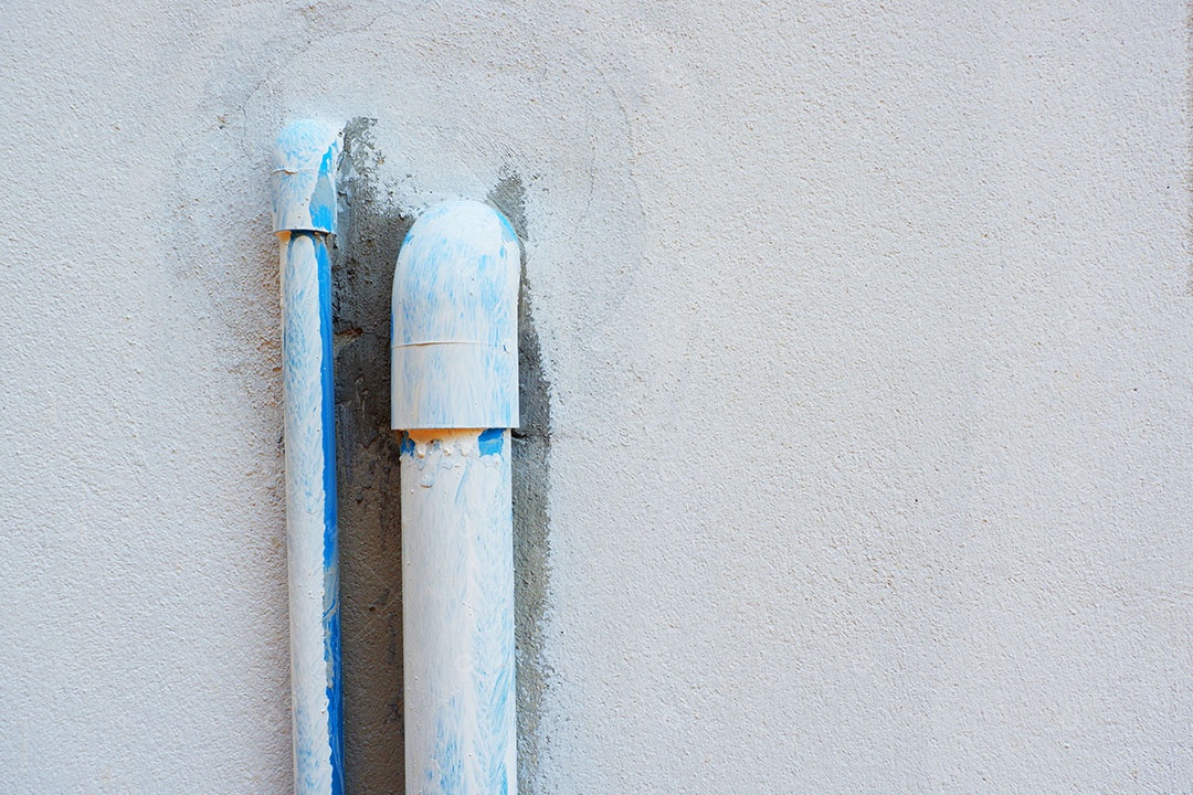 Canos de água de PVC são instalados atrás da casa.
