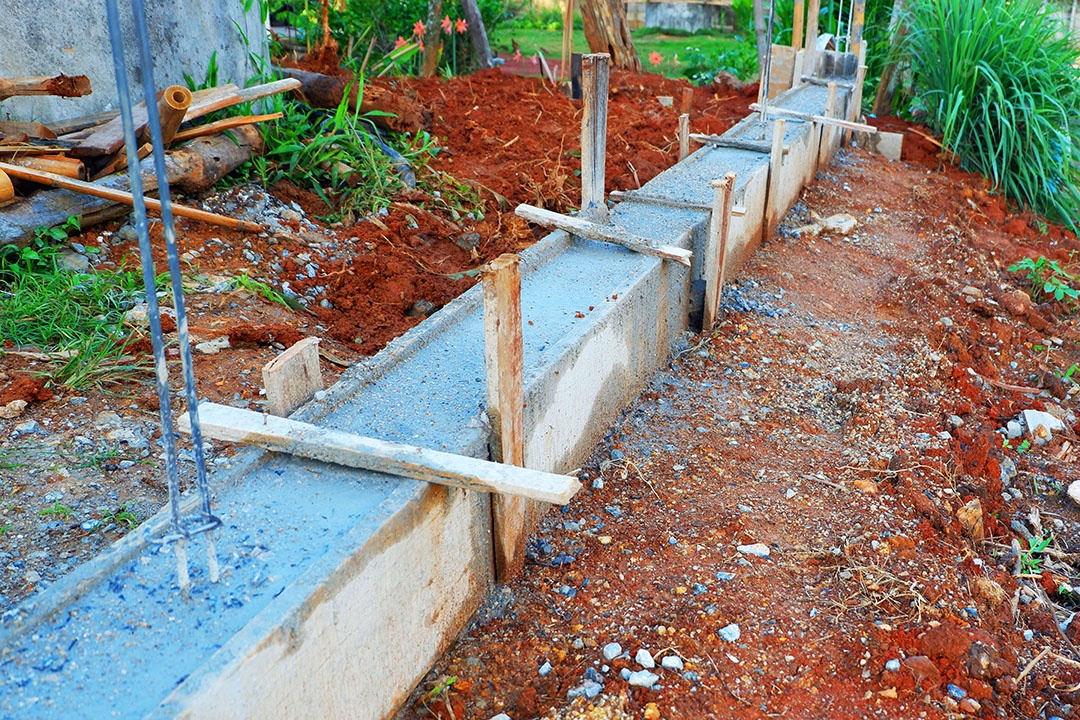 Construção de viga de cimento da base da cerca da casa perto da estrada de concreto