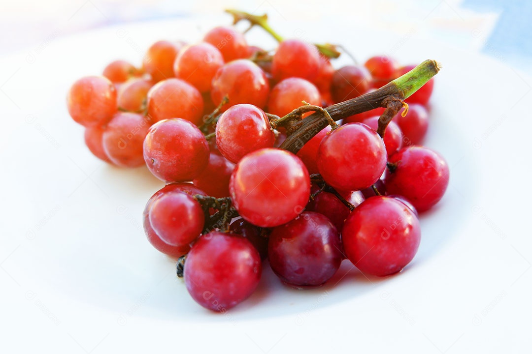 Uvas vermelha sobre prato branco
