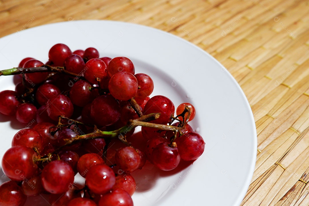 Uvas vermelha sobre prato branco
