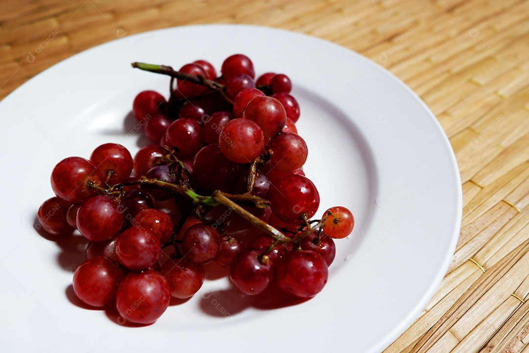 Uvas vermelha sobre prato branco