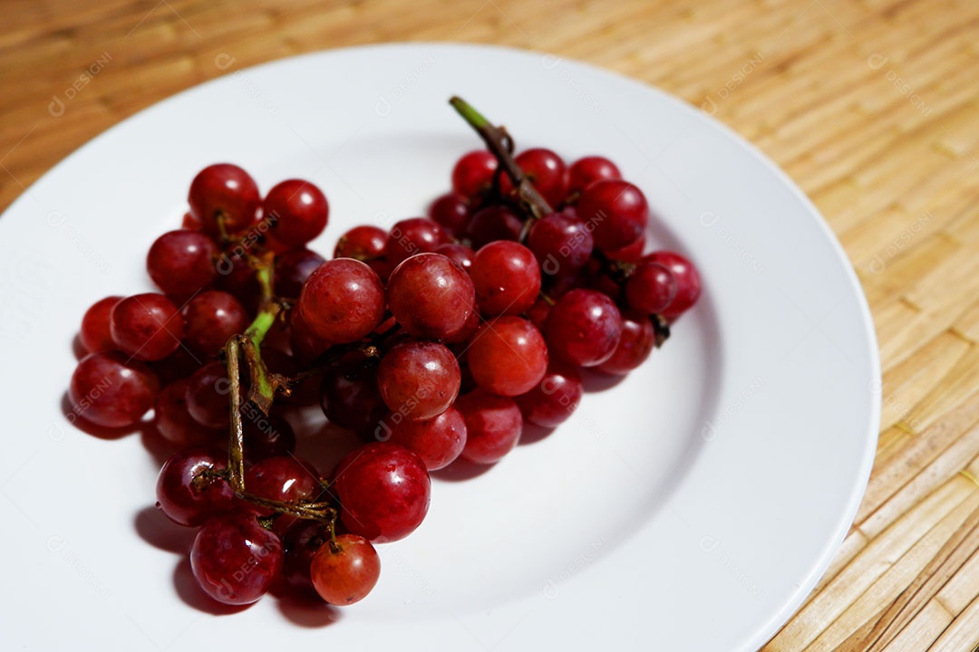 Uvas vermelha sobre prato branco