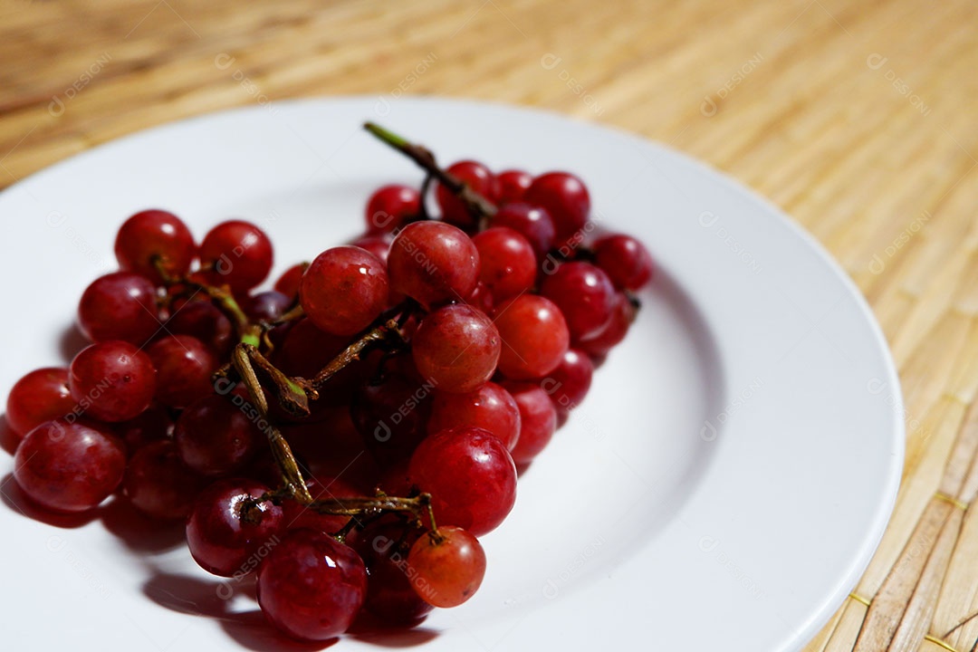 Uvas vermelha sobre prato branco