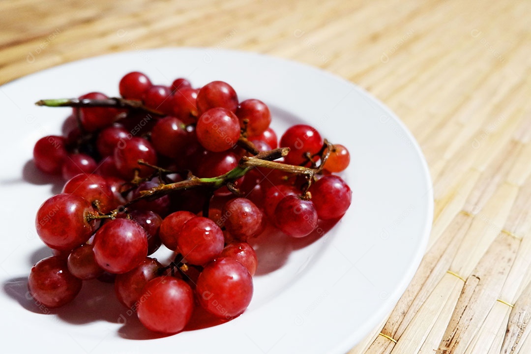 Uvas vermelha sobre prato branco