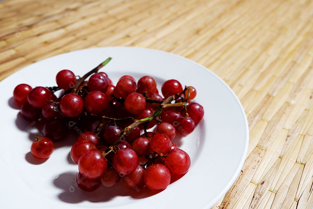 Uvas vermelha sobre prato branco