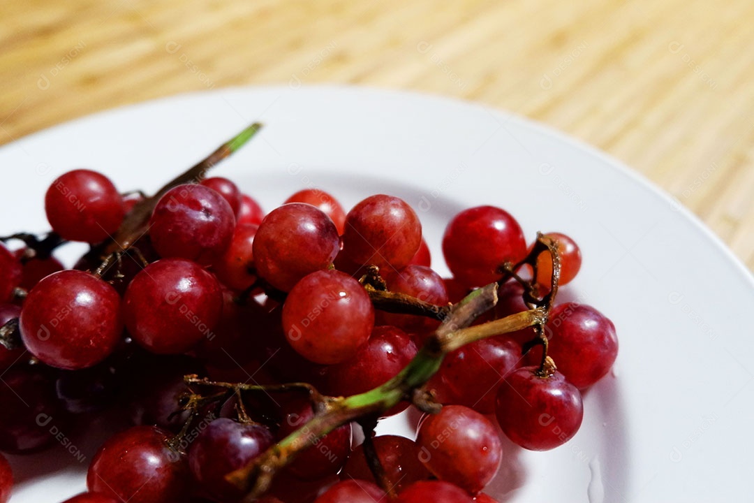 Uvas vermelha sobre prato branco