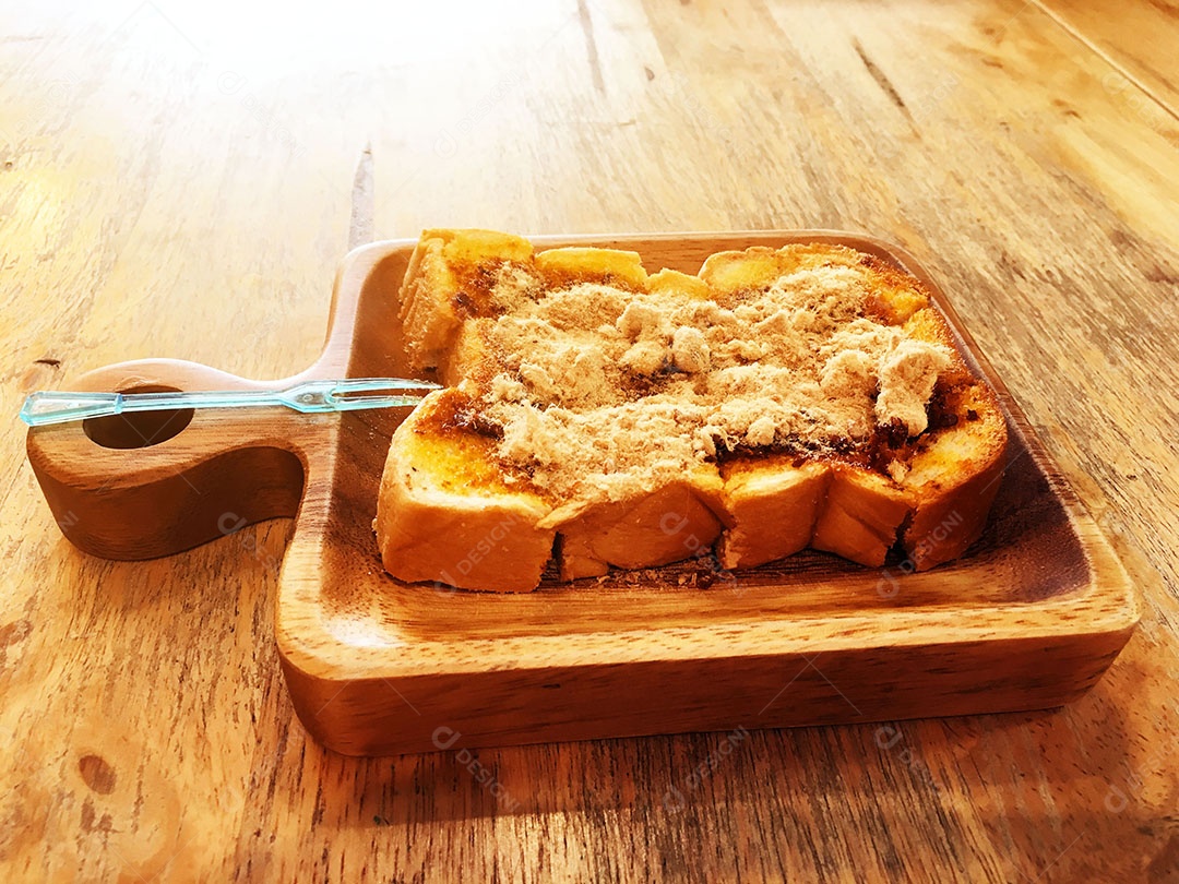 Pão torrado com carne de porco desfiada seca e pasta de pimentão em prato quadrado de madeira está na mesa de madeira