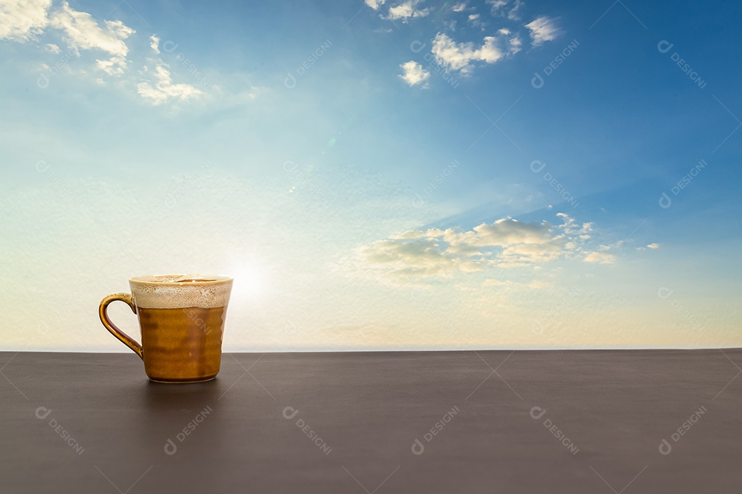 Caneca de café está sobre a mesa com vista para o céu e nuvens