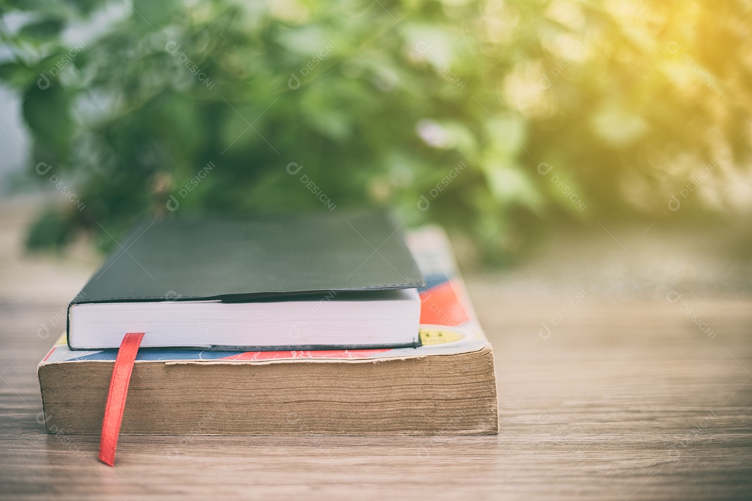 Livro antigo na mesa de madeira no jardim de casa com fundo de natureza bokeh