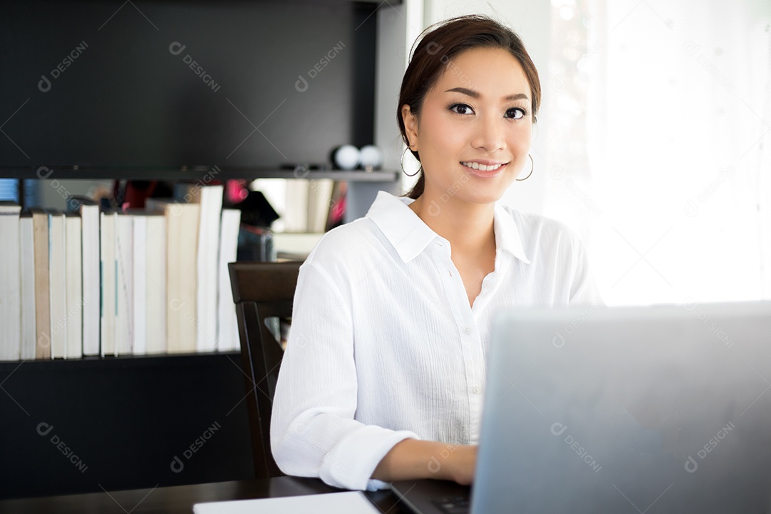 Mulher de negócios asiáticos usando notebook e sorrindo felizes por trabalhar