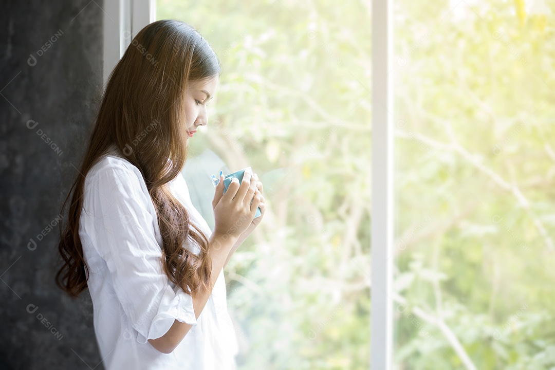 Mulher asiática tomando café no sol da manhã